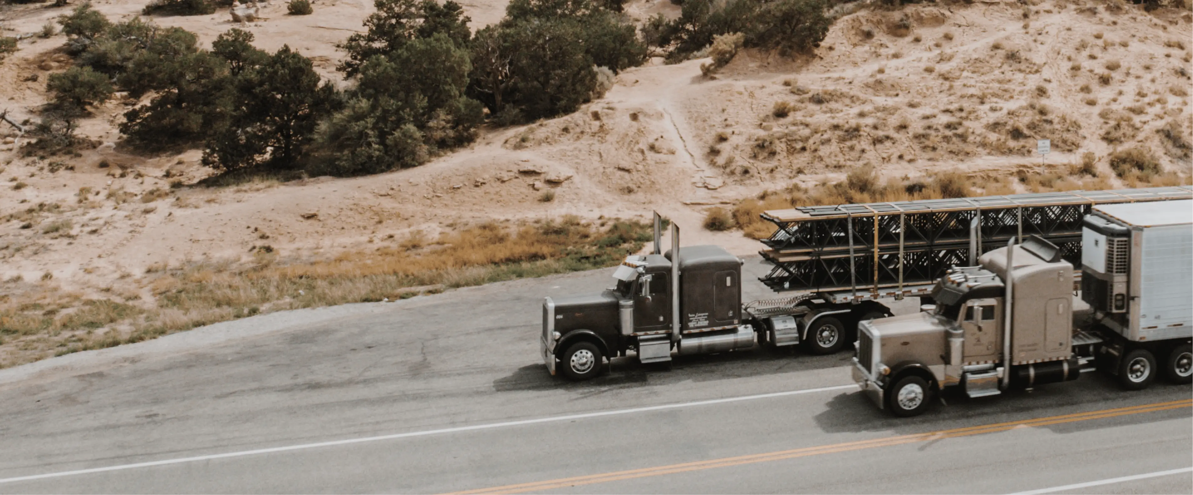 Two semi-trucks parked along a desert roadside for LeCoop Truck and Trailer transportation services