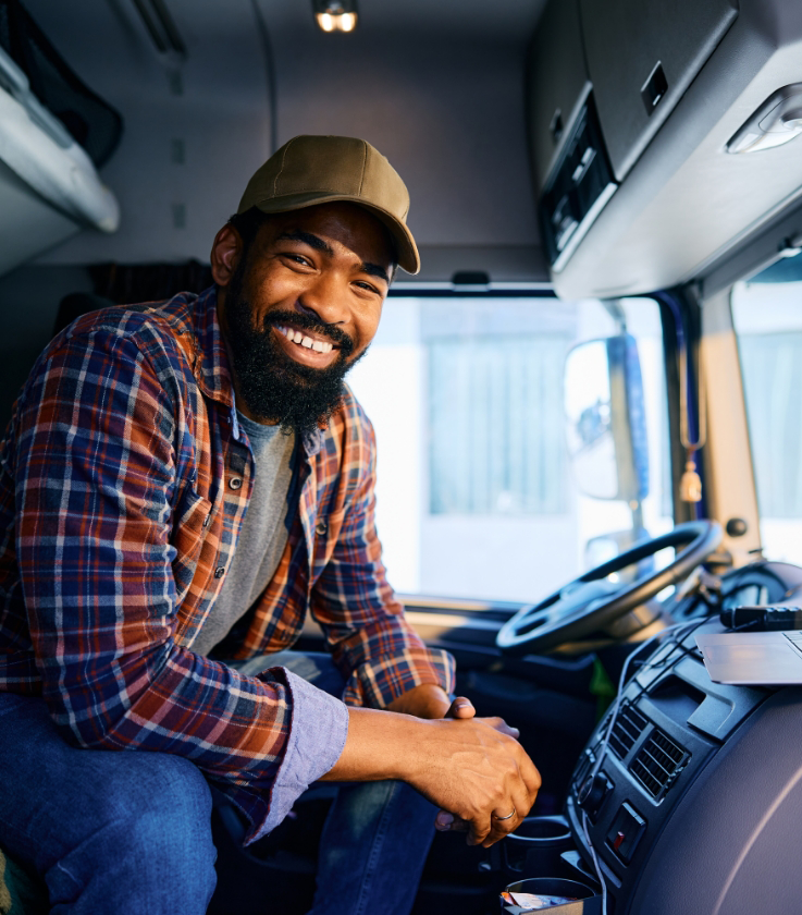 Smiling truck driver sitting inside a commercial truck cab for LeCoop Truck and Trailer services